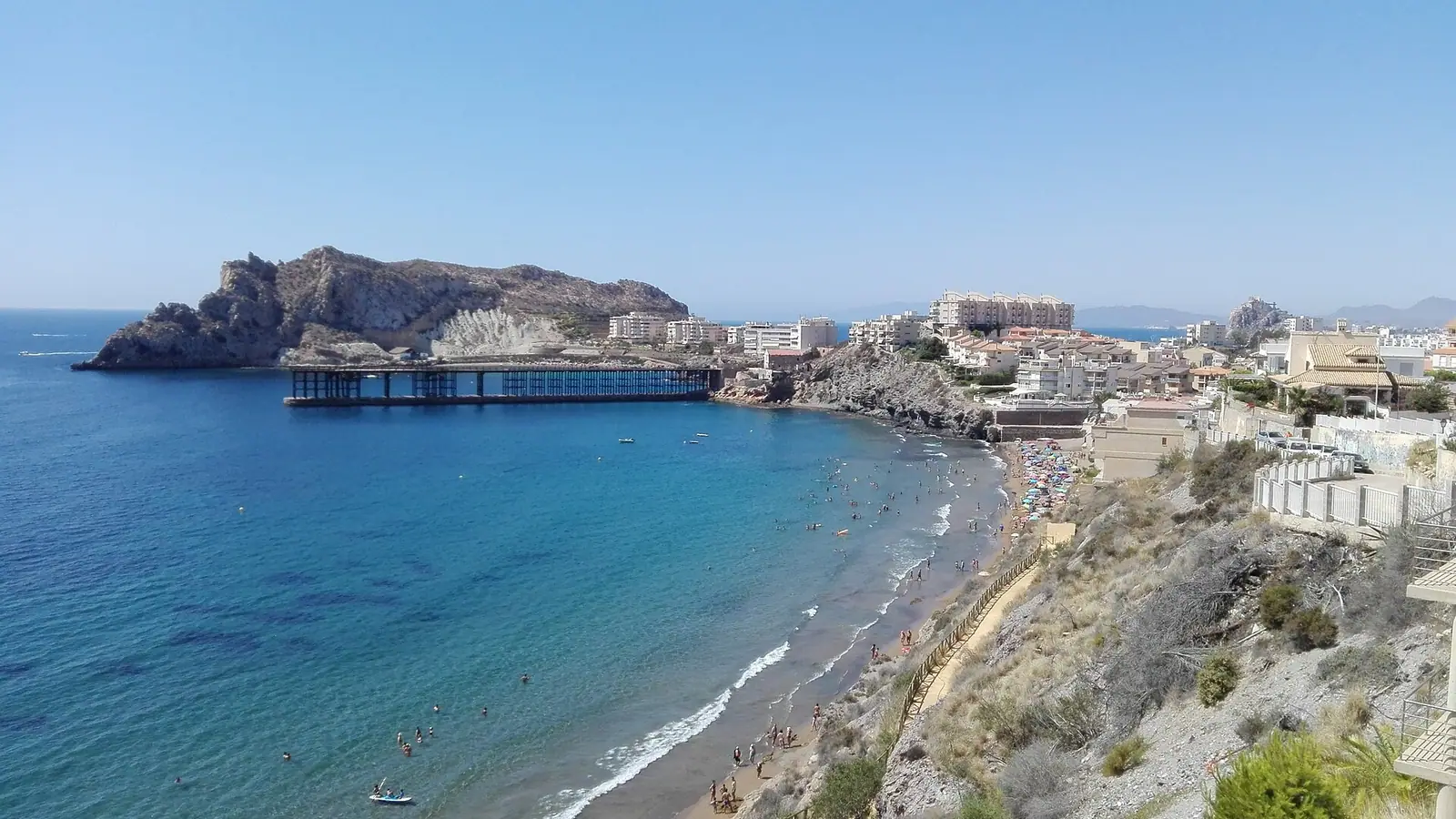 Águilas – Vista panorámica de la Playa del Hornillo en Águilas (Murcia). Pertenece a la llamada Costa Cálida por la temperatura de sus aguas. Al fondo puede verse el antiguo Cargadero de mineral de Águilas, hoy en desuso.