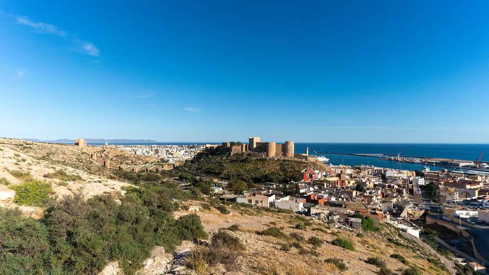 Almería – Elevated view from the mountain over Almería, Spain, showing the bay, the Alcazaba fortress on its hill above the old town, and the harbour with the Mediterranean Sea in the background.