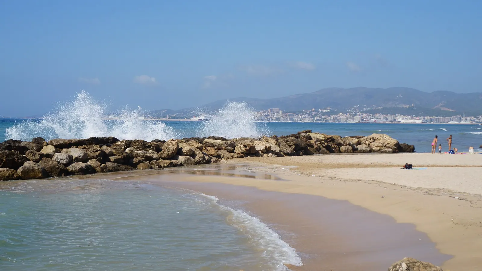 Palma de Mallorca – Rubble-mound groyne at Platja de Palma in Can Pastilla, with the Bay of Palma, the urban coastline of Palma and the Serra de na Burguesa in the background.