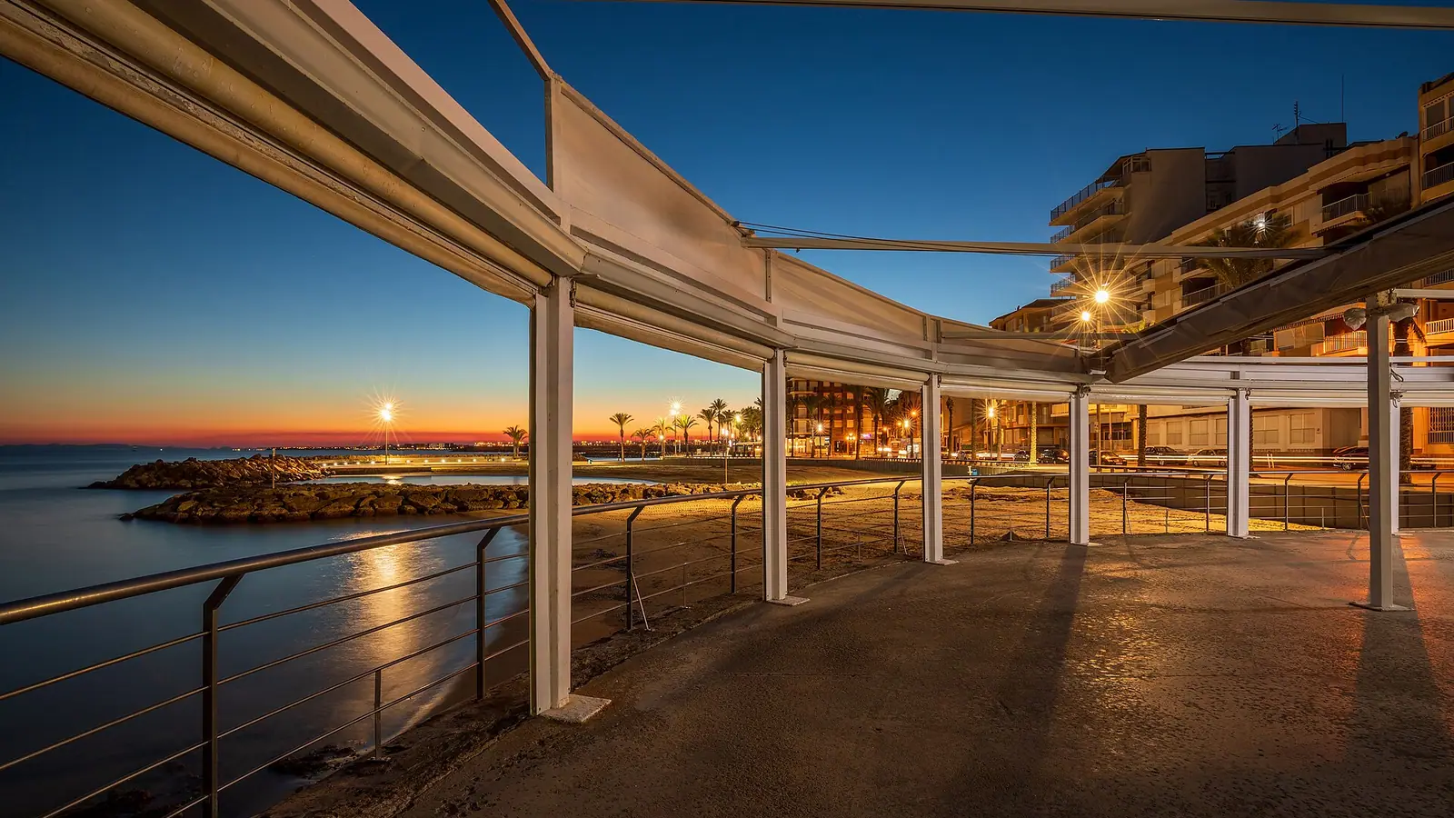 Torrevieja – A coastal cityscape of Las Rocas in evening from Kiosco El Tintero in Playa del Cura, Torrevieja, Alicante, Spain in 2022 January.